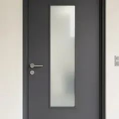 Nowoczesne, szare drzwi zewnętrzne z matową szybą i metalową klamką. Idealne, jakie drzwi zewnętrzne do minimalistycznego domu.