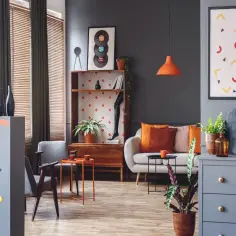 Sofa z poduszkami w kolorze morelowym i pomarańczowym, obok stolik kawowy i fotel.