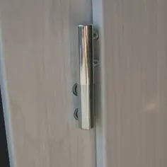Metalowy zawias na jasnych drzwiach, element regulacji drzwi na zawiasach.