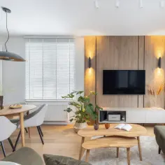 Przytulny salon z jadalnią, gdzie ciepłe kolory drewna i oświetlenia tworzą relaksującą atmosferę.