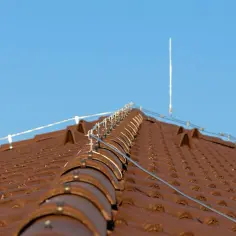 Nowy dach z brązowej dachówki, na którym zamontowano nowoczesną instalację odgromową, chroniącą przed burzami.