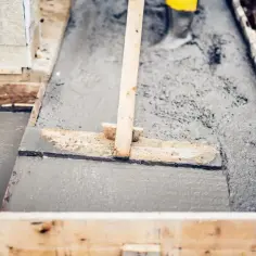Praca przy budowie, świeży beton wylewany do szalunku. Zastanawiasz się, ile waży m3 betonu? To ważna kwestia przy planowaniu budowy.