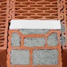 Fragment budowy z pustaków ceramicznych, widoczne spoiny zaprawy i izolacja. Pustak ceramiczny wymiary są kluczowe dla tej konstrukcji.