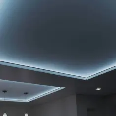 Nowoczesny sufit napinany z subtelnym, niebieskim podświetleniem tworzy atmosferę relaksu.