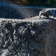 Ręka w rękawicy wygładza świeży beton. Zastanawiasz się, ile kosztuje m3 betonu? To ważna inwestycja w budowę.