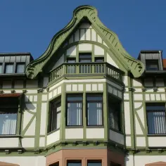 Elegancki ryzalit co to? Wystający fragment fasady budynku z zielonymi zdobieniami i balkonem.