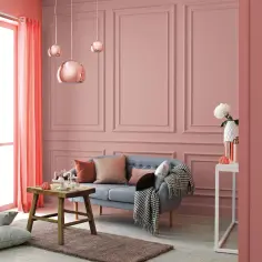 Przytulny salon z kanapą, stolikiem i zasłonami w odcieniu różu. Ściany mają subtelny, **kolor słomkowy**, a miedziane lampy dodają blasku.