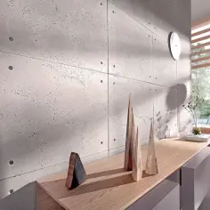 Nowoczesne wnętrze z widocznym efektem surowego betonu na ścianie. Drewniane dekoracje i jasne meble tworzą minimalistyczną przestrzeń.