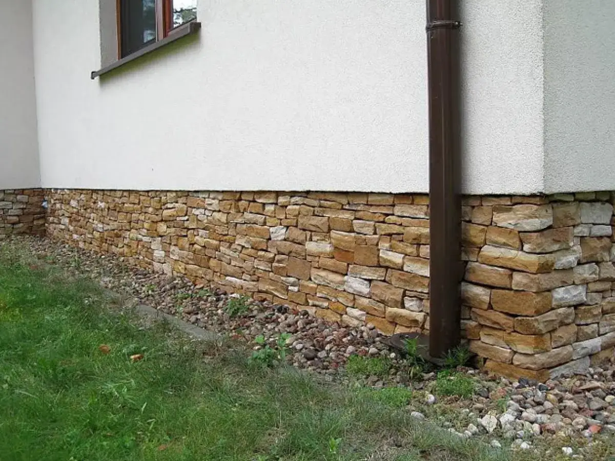 Kamienny cokół domu, ozdobiony naturalnym kamieniem, chroni ściany przed wilgocią.