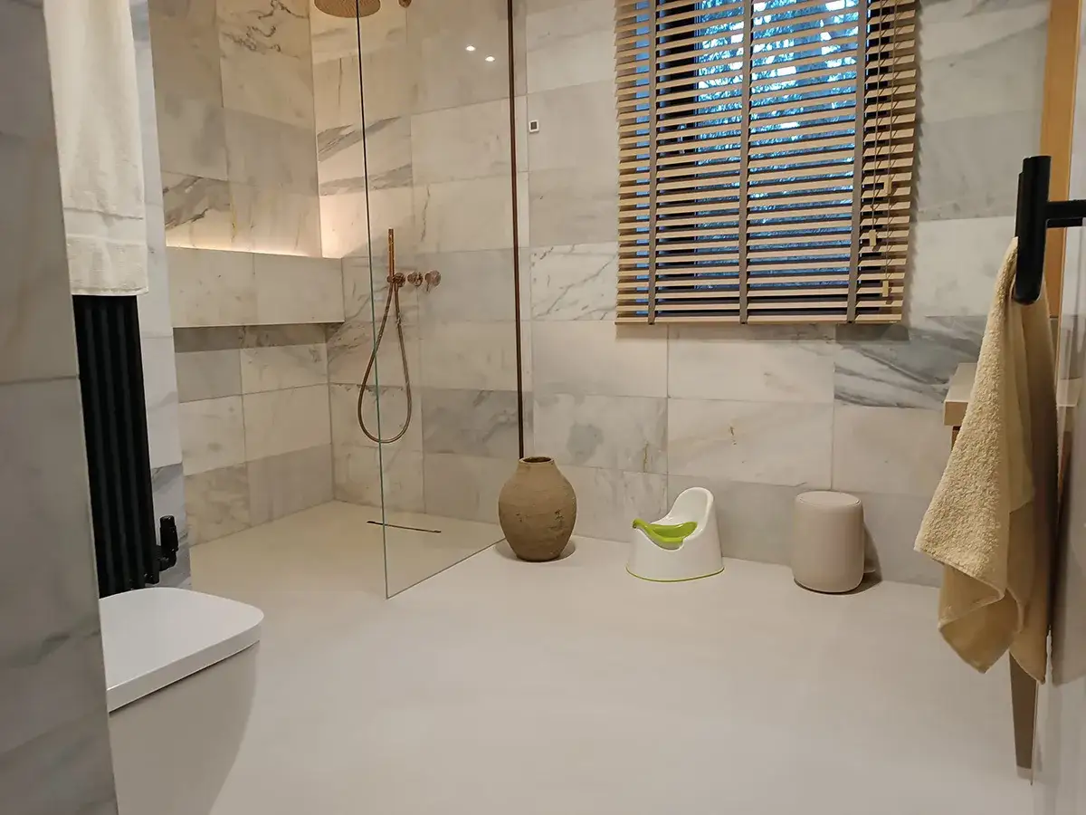 Nowoczesna mikrocement łazienka z prysznicem walk-in, toaletą i dziecięcym nocnikiem.