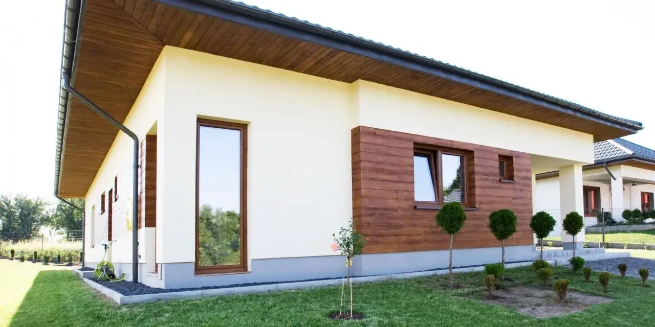 Nowoczesny dom z jasnym tynkiem silikonowym i drewnianą elewacją. Sprawdź tynk silikonowy cena za m2 robocizny.