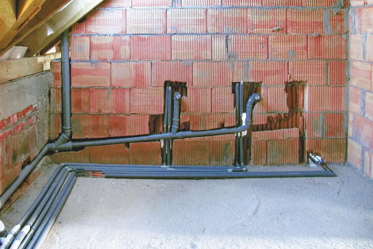 Instalacja hydrauliczna z rurami PVC, z widocznym minimalnym spadkiem dla rury 110, w trakcie budowy.