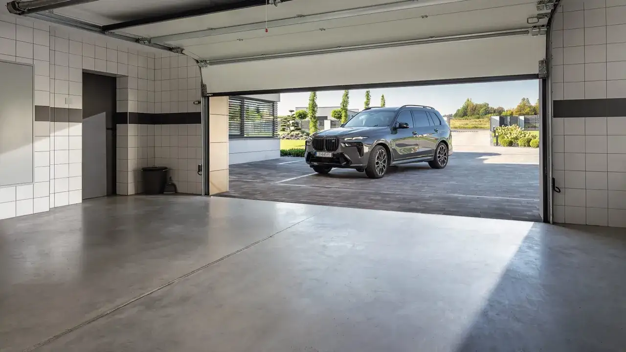 Szara, betonowa posadzka w garażu, na której stoi luksusowy SUV.