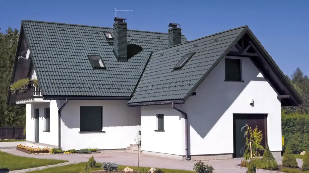 Nowoczesny dom z białymi ścianami i zielonym, dach wielospadowy. Dwa kominy i okna dachowe.